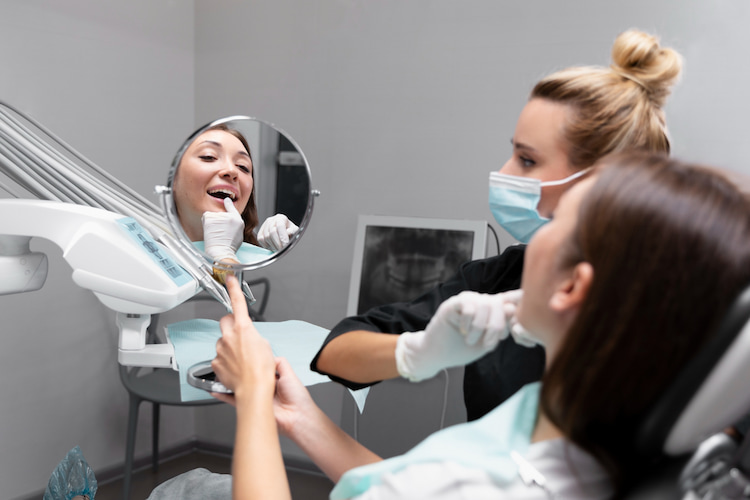 a cosmetic dentist is showing something in a patient's teeth in the mirror.